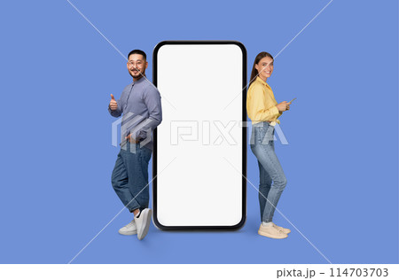 A man and woman stand with a blank smartphone display mockup on blue, mockup copy space for mobile app ad A man and woman stand with a blank smartphone display mockup on blue, mockup copy space for mobile app ad 114703703