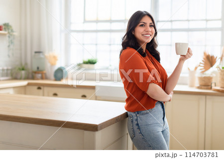 Portrait of a confident middle eastern woman with a mug, in a home setting, suggesting domestic comfort, copy space Portrait of a confident middle eastern woman with a mug, in a home setting, suggesting domestic comfort, copy space 114703781