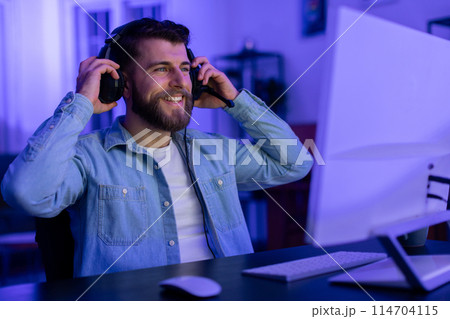 In the comfort of his home, this millennial guy tweaks his headset, a staple for the modern gamer and indicative of his dedication and addiction to gaming 114704115
