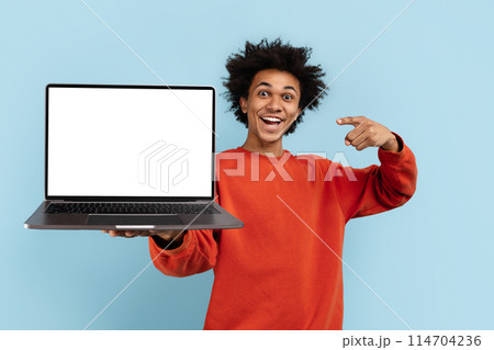 An enthusiastic african american presenting a laptop screen, isolated on blue, perfect for mockups and advertising spaces 114704236