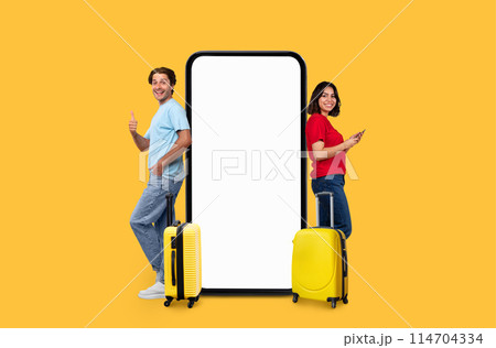 A joyful couple with suitcases pose by a large phone display with a blank screen, perfect for travel-related application ads on an isolated yellow background A joyful couple with suitcases pose by a large phone display with a blank screen, perfect for travel-related application ads on an isolated yellow background 114704334
