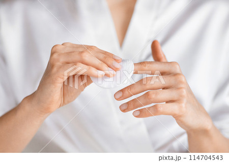 A millennial woman is captured applying a skin care product in her bright, soothing bathroom, focusing on self-care and beauty routines, doing manicure 114704543