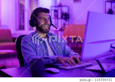 With intense concentration, this millennial guy epitomizes a gamer deeply invested in his match, reflecting the addiction and engagement of home gaming With intense concentration, this millennial guy epitomizes a gamer deeply invested in his match, reflecting the addiction and engagement of home gaming 114704731