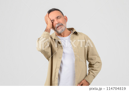 An elderly man holds his head, depicting a stressful or painful moment, isolated on white, have migraine 114704819