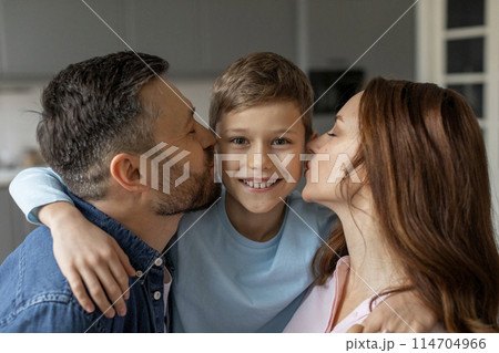 A heartwarming image capturing a young boy smiling as his parents affectionately kiss him on the cheeks, in a cozy home setting A heartwarming image capturing a young boy smiling as his parents affectionately kiss him on the cheeks, in a cozy home setting 114704966