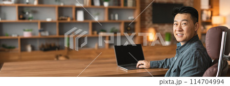 Happy confident successful adult korean man typing on computer with blank screen at workplace in office interior. Economic, investment, technology for modern business remotely, copy space 114704994