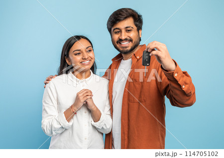 Content Indian couple showing off a car key, implying a new vehicle purchase or ownership on blue 114705102