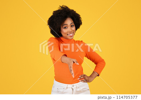 Smiling woman with curly hair in orange turtleneck offering a handshake, portraying a friendly and professional gesture, paired with white pants, on a cheerful yellow background Smiling woman with curly hair in orange turtleneck offering a handshake, portraying a friendly and professional gesture, paired with white pants, on a cheerful yellow background 114705377
