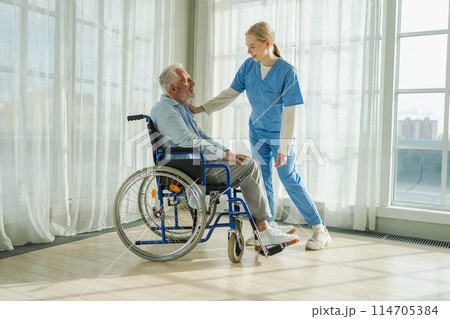 Help support retirement healthcare. Nurse helping old man in wheelchair. Patient and woman in nursing home for medical caregiver. Nurse taking care of paralyzed man in chair for people with disability Help support retirement healthcare. Nurse helping old man in wheelchair. Patient and woman in nursing home for medical caregiver. Nurse taking care of paralyzed man in chair for people with disability 114705384
