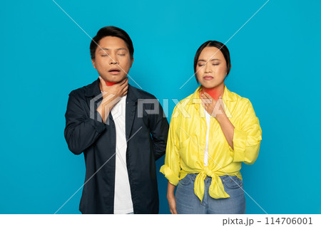 A millennial japanese man and woman in bright clothing touch their throats with closed eyes and uncomfortable expressions, suggesting difficulty in breathing or sore throat A millennial japanese man and woman in bright clothing touch their throats with closed eyes and uncomfortable expressions, suggesting difficulty in breathing or sore throat 114706001