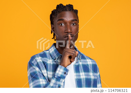 Keep Silence. Portrait Of Young Black Guy Showing Shh Gesture At Camera, Millennial African American Man Holding Finger Near Lips, Gesturing Hush While Standing Isolated On Yellow Studio Background 114706321