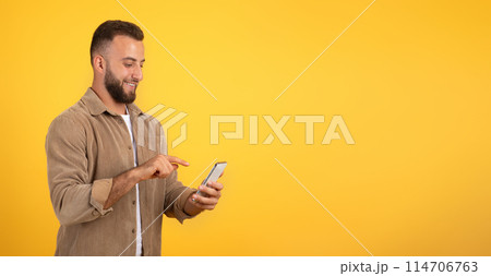 Positive european millennial guy with beard chatting on mobile phone, using app for blog, social networks, isolated on orange studio background, panorama. Work remotely, ad and offer Positive european millennial guy with beard chatting on mobile phone, using app for blog, social networks, isolated on orange studio background, panorama. Work remotely, ad and offer 114706763