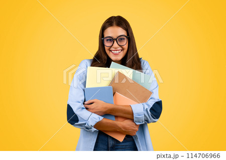 Glad teenager student woman in glasses hug many books, enjoy study and lifestyle, isolated on yellow studio background. Education at school, ad and offer, prepare to exam Glad teenager student woman in glasses hug many books, enjoy study and lifestyle, isolated on yellow studio background. Education at school, ad and offer, prepare to exam 114706966