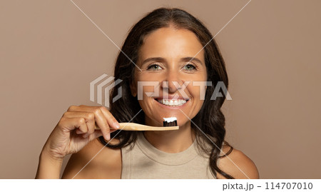 Cheerful caucasian senior woman brushing teeth with toothbrush, enjoy oral care, isolated on beige studio background, panorama. Dental care, dentistry, routine procedures Cheerful caucasian senior woman brushing teeth with toothbrush, enjoy oral care, isolated on beige studio background, panorama. Dental care, dentistry, routine procedures 114707010