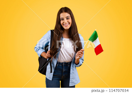 Smiling european teenager student pupil, with Italian flag, enjoy exchange study, courses, isolated on yellow background. Lifestyle, national pride and learning Italian language 114707034