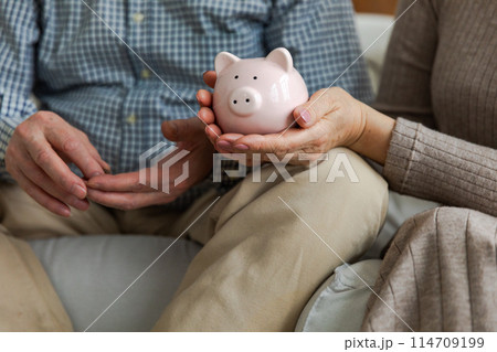 Saving money investment for future. Senior adult mature couple hands holding piggy bank with money coin. Old man woman counting saving money planning retirement budget. Investment banking concept 114709199
