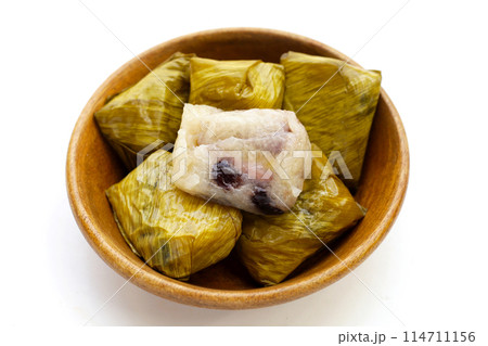Bundled boiled sticky rice with banana and black beans wrapped in banana leaves 114711156