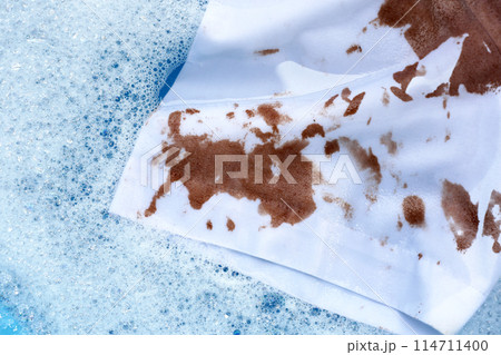 Dirty choclate stain on white shirt in water with detergent water dissolution, washing cloth Dirty choclate stain on white shirt in water with detergent water dissolution, washing cloth 114711400