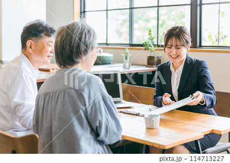 高齢者から資産運用・保険の相談を受けるアジア人ビジネスウーマン・プランナー・コンサルタント 114713227