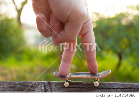 A man's fingers ride a small skateboard like a little man 114714066