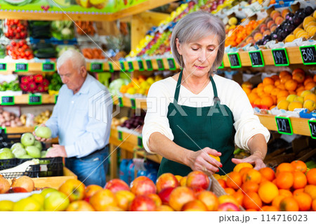 Mature woman supermarket worker and senior man customer in salesroom 114716023