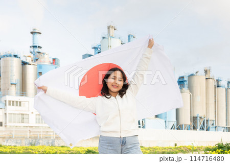 Happy young woman with flag of Japan against background of factory Happy young woman with flag of Japan against background of factory 114716480