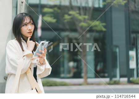街角で悩んでいるスマホを持った若い女性 街角で悩んでいるスマホを持った若い女性 114716544