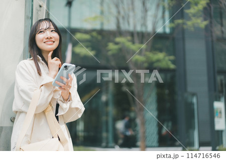 街でスマホを持った若い女性が嬉しい悩みを感じているシーン 114716546