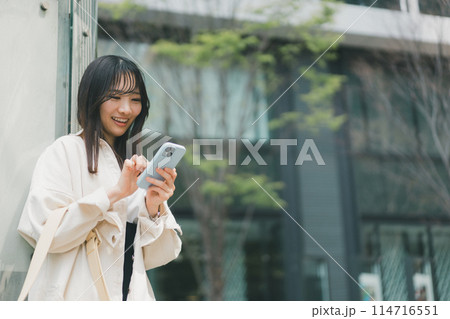 街中でスマホを操作する若い女性 114716551