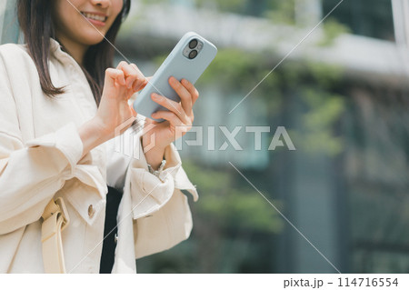 街でスマホを操作する若い女性 114716554