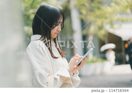 公共の場でスマホを操作する若い女性 公共の場でスマホを操作する若い女性 114716564