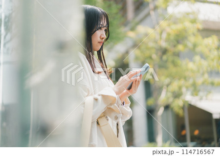 待ち合わせ場所に友達が来なくて不安な若い女性がスマホに連絡が来ているか確認している場面のイメージ 待ち合わせ場所に友達が来なくて不安な若い女性がスマホに連絡が来ているか確認している場面のイメージ 114716567