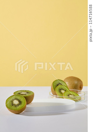 Concept of healthy skin with slices and halves of kiwi displayed with a podium on yellow background. Vacant space on the podium to show product of Kiwi fruit extract Concept of healthy skin with slices and halves of kiwi displayed with a podium on yellow background. Vacant space on the podium to show product of Kiwi fruit extract 114716588