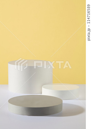 Cylinder and round shaped podiums in white and gray color are arranged against yellow background. Glamour minimal pedestal for beauty, cosmetic product presentation Cylinder and round shaped podiums in white and gray color are arranged against yellow background. Glamour minimal pedestal for beauty, cosmetic product presentation 114716589