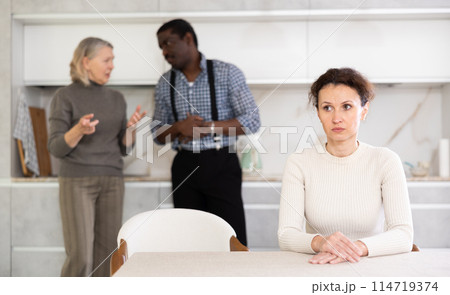 Adult sad woman sitting at table during family quarrel Adult sad woman sitting at table during family quarrel 114719374
