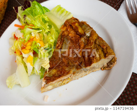 Artichoke omelette served with vegetable salad 114719436
