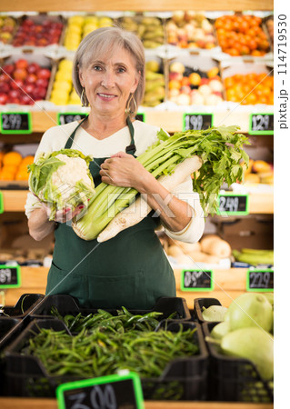 Mature lady supermarket worker with vegetables in hands 114719530