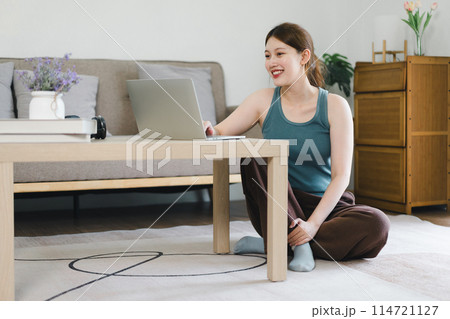 Young woman working on laptop at home during daytime in cozy living room. Young woman working on laptop at home during daytime in cozy living room. 114721127