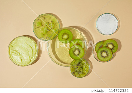 Advertising photo of high angle shot, a glass dish containing light green fluid and some slices of kiwi decorated, chopped kiwi, kiwi slices, white and yellow exfoliation cream. Vacant space for text Advertising photo of high angle shot, a glass dish containing light green fluid and some slices of kiwi decorated, chopped kiwi, kiwi slices, white and yellow exfoliation cream. Vacant space for text 114722522