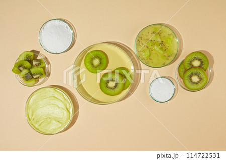 Plenty glass dishes displayed on light yellow counter top, a blank dish in center with some kiwi slices above, next to it are some dishes of exfoliating cream and fresh kiwi. Template for designing Plenty glass dishes displayed on light yellow counter top, a blank dish in center with some kiwi slices above, next to it are some dishes of exfoliating cream and fresh kiwi. Template for designing 114722531