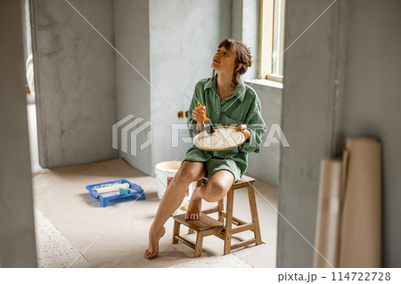 Woman paints walls renovating her apartment 114722728