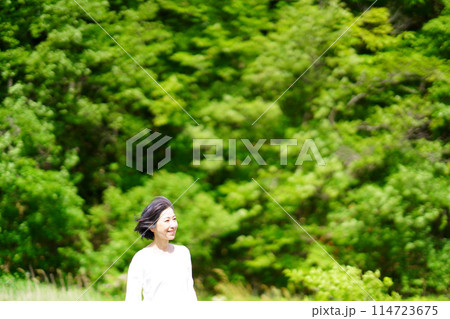 緑の中気持ちよさそうに髪を風になびかせる中年女性 緑の中気持ちよさそうに髪を風になびかせる中年女性 114723675