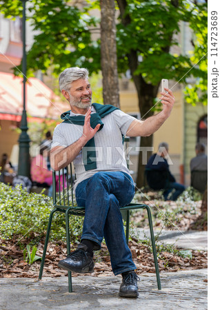 Mature man blogger use smartphone communicating video call online with subscribers recording stories 114723689