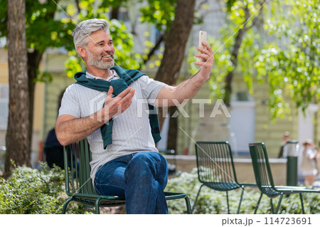Mature man blogger use smartphone communicating video call online with subscribers recording stories 114723691