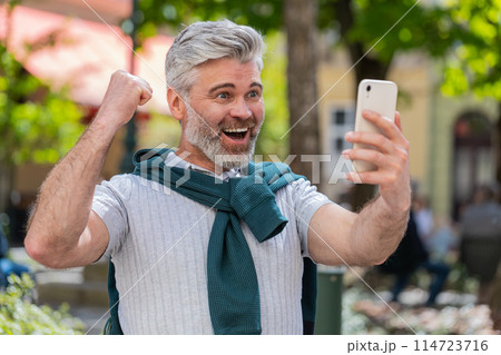 Happy man use mobile smartphone celebrating win good message news lottery jackpot casino app victory 114723716