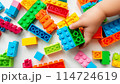 Kid hand building up a wall by stacking up the colorful wall block brick toy for banner, children sale promotion, flyer, online shop, poster, web, ads, and social media. Toddler Playing with colorful 114724619