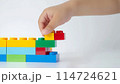 Kid hand building up a wall by stacking up the colorful wall block brick toy for banner, children sale promotion, flyer, online shop, poster, web, ads, and social media. Toddler Playing with colorful 114724621