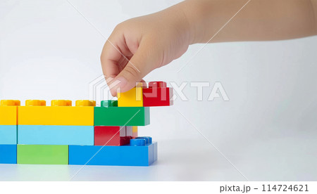 Kid hand building up a wall by stacking up the colorful wall block brick toy for banner, children sale promotion, flyer, online shop, poster, web, ads, and social media. Toddler Playing with colorful 114724621