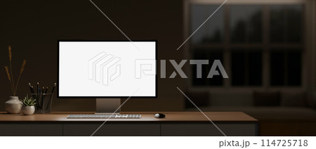A comfortable home office workspace at night features a computer mockup on a table in the dark room. 114725718