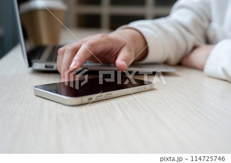 A close-up image of a woman touching on her smartphone screen, checking messages while working. A close-up image of a woman touching on her smartphone screen, checking messages while working. 114725746